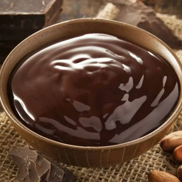 A close-up image of homemade sugar-free chocolate squares arranged on a wooden board, garnished with cocoa powder and fresh mint leaves.